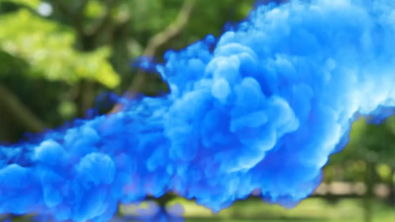 A gulal popper firing a dense column of blue colour powder outdoors