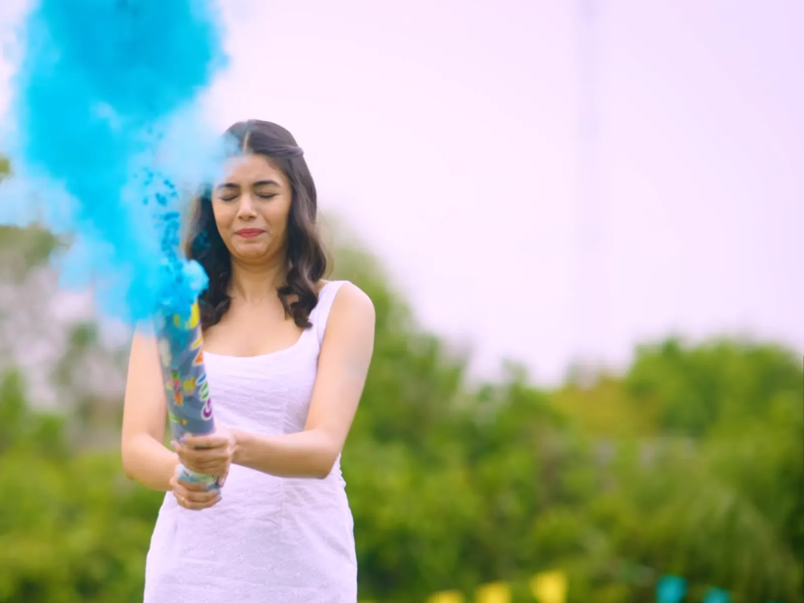 A gulal popper firing a column of blue colour powder