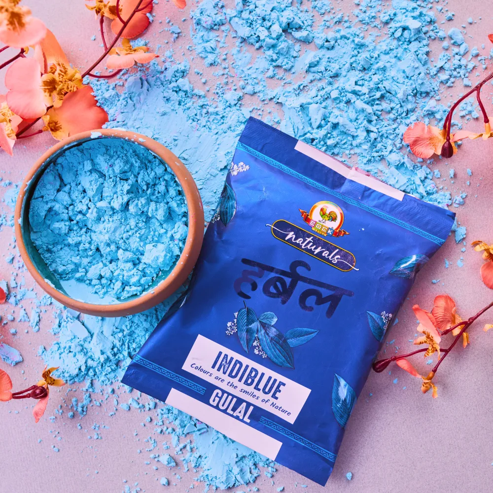 Indiblue herbal gulal pack beside a bowl of blue pigment